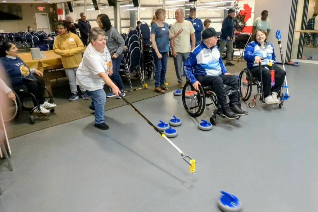 A participant in White Rock&rsquo;s first Adaptive Curling session on Feb. 4 delivers a &lsquo;stone&rsquo; with the aid of an extended delivery stick at the upstairs practice area for Peace Arch Curling Club, in the Centre for Active Living. (Alex Browne/Peace Arch News)
